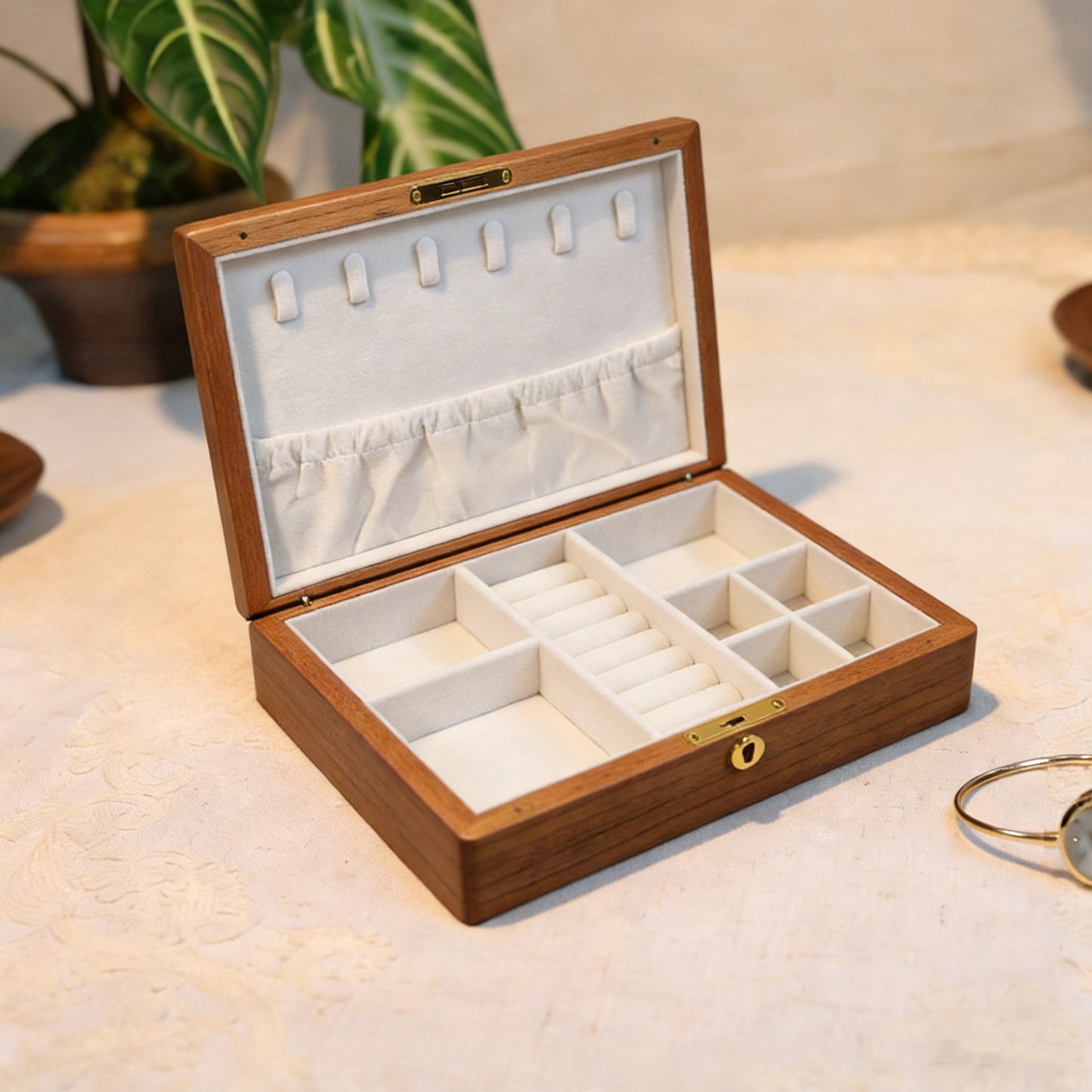 Wooden jewelry box with white interior on a light surface