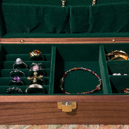Jewelry box with green interior displaying various jewelry items, including bracelets and necklaces.