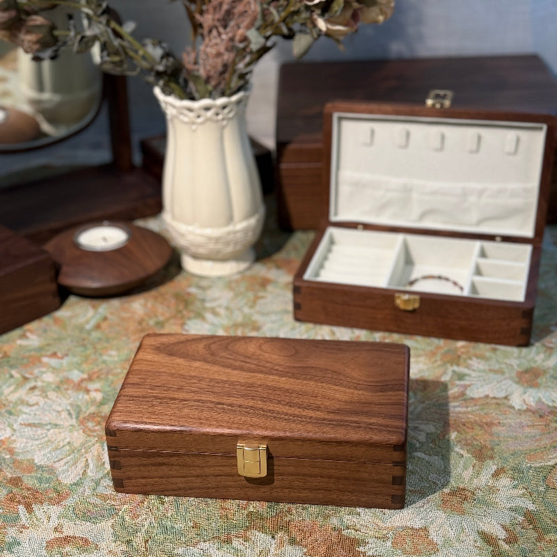 Wooden jewelry box on a floral-patterned surface with another box in the background.