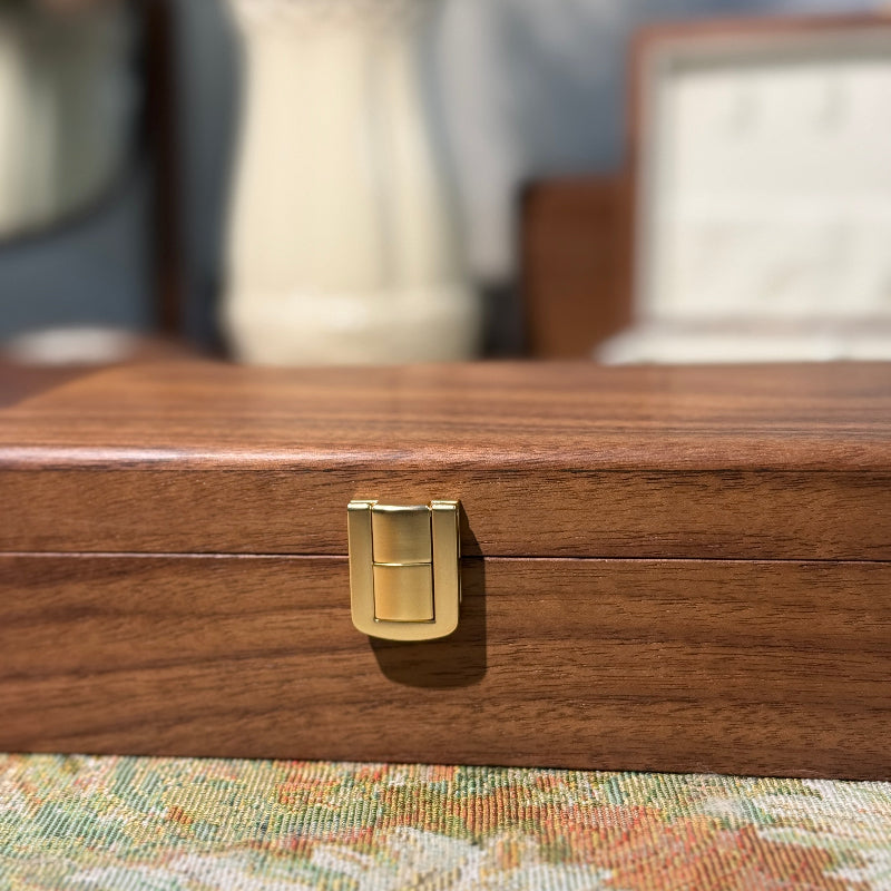 Wooden jewelry box with a gold clasp on a floral-patterned surface
