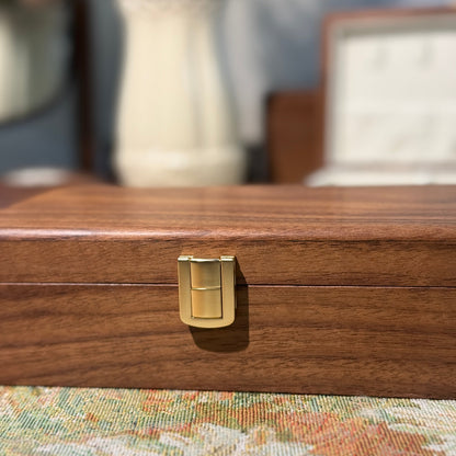 Wooden jewelry box with a gold clasp on a floral-patterned surface