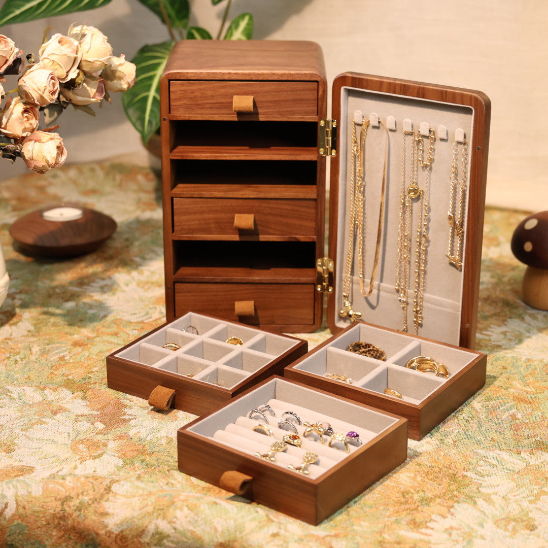 Wooden jewelry box with compartments on a floral tablecloth.