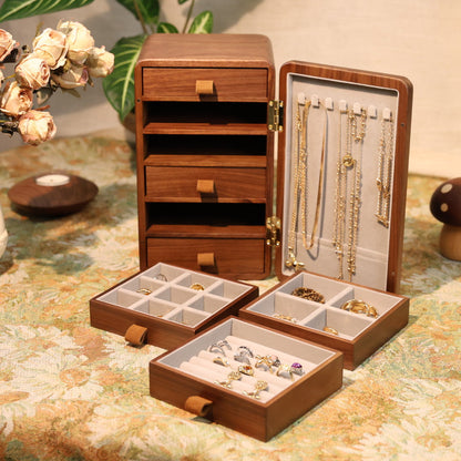 Wooden jewelry box with compartments on a floral tablecloth.