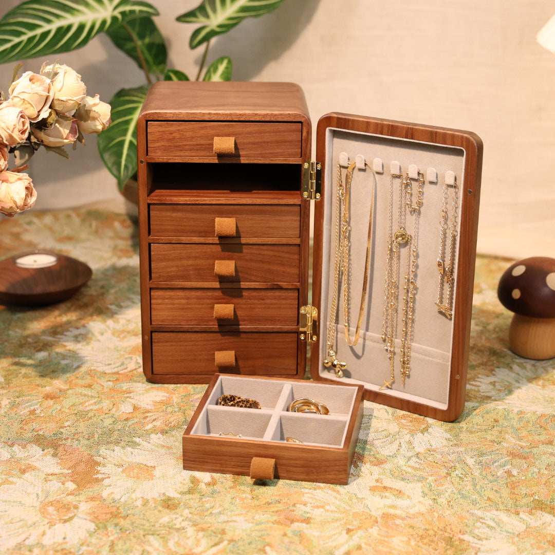 Wooden jewelry organizer with drawers and display case on a floral tablecloth.