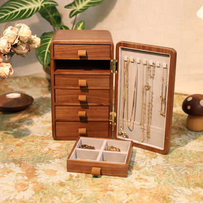 Wooden jewelry organizer with drawers and display case on a floral tablecloth.