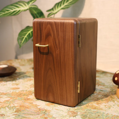 Wooden box with a gold handle on a decorative surface with plants and a lamp in the background