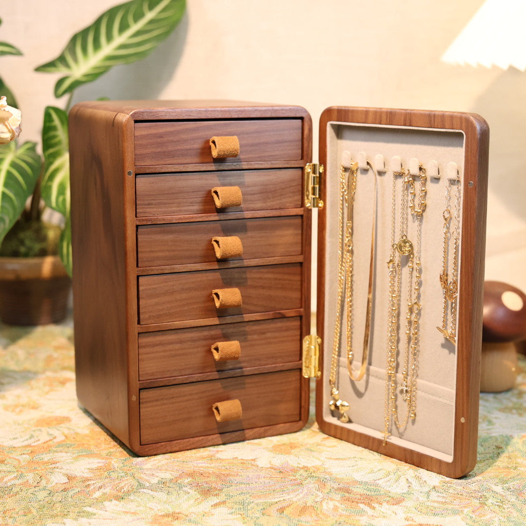 Wooden jewelry box with open lid displaying necklaces on a patterned surface.