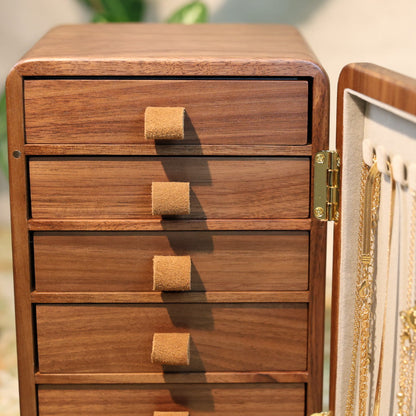 Wooden jewelry box with open lid displaying necklaces on a blurred background