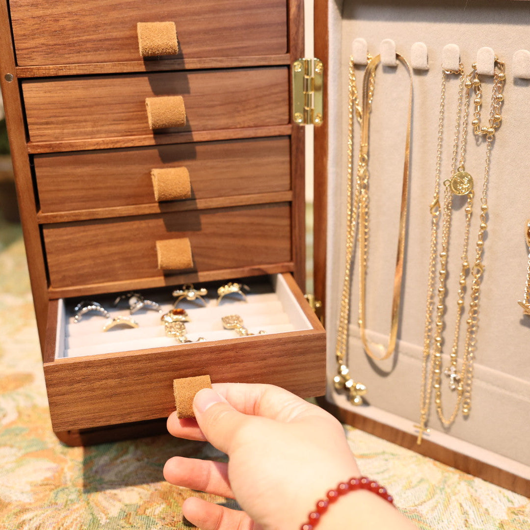 Wooden jewelry box with necklaces and a hand reaching inside