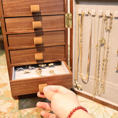Wooden jewelry box with necklaces and a hand reaching inside