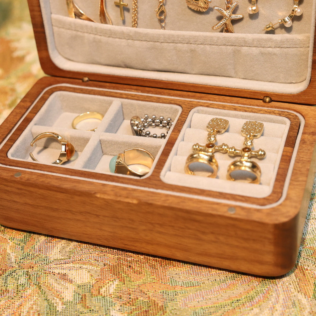 Wooden jewelry box with gold earrings and rings on a patterned fabric background