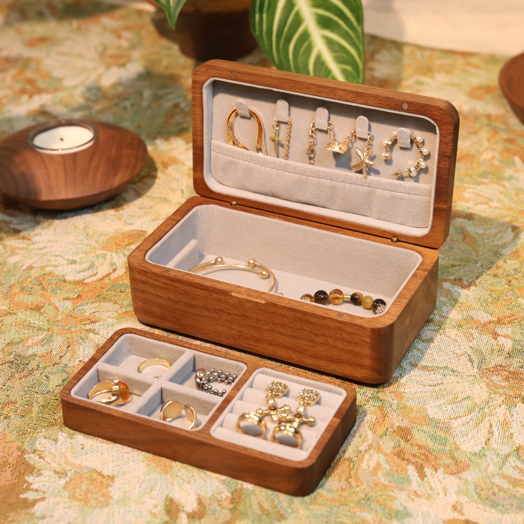 Wooden jewelry box with compartments filled with earrings on a patterned surface