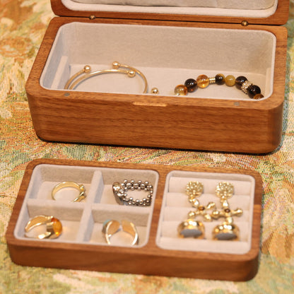 Wooden jewelry box with compartments containing jewelry on a patterned surface