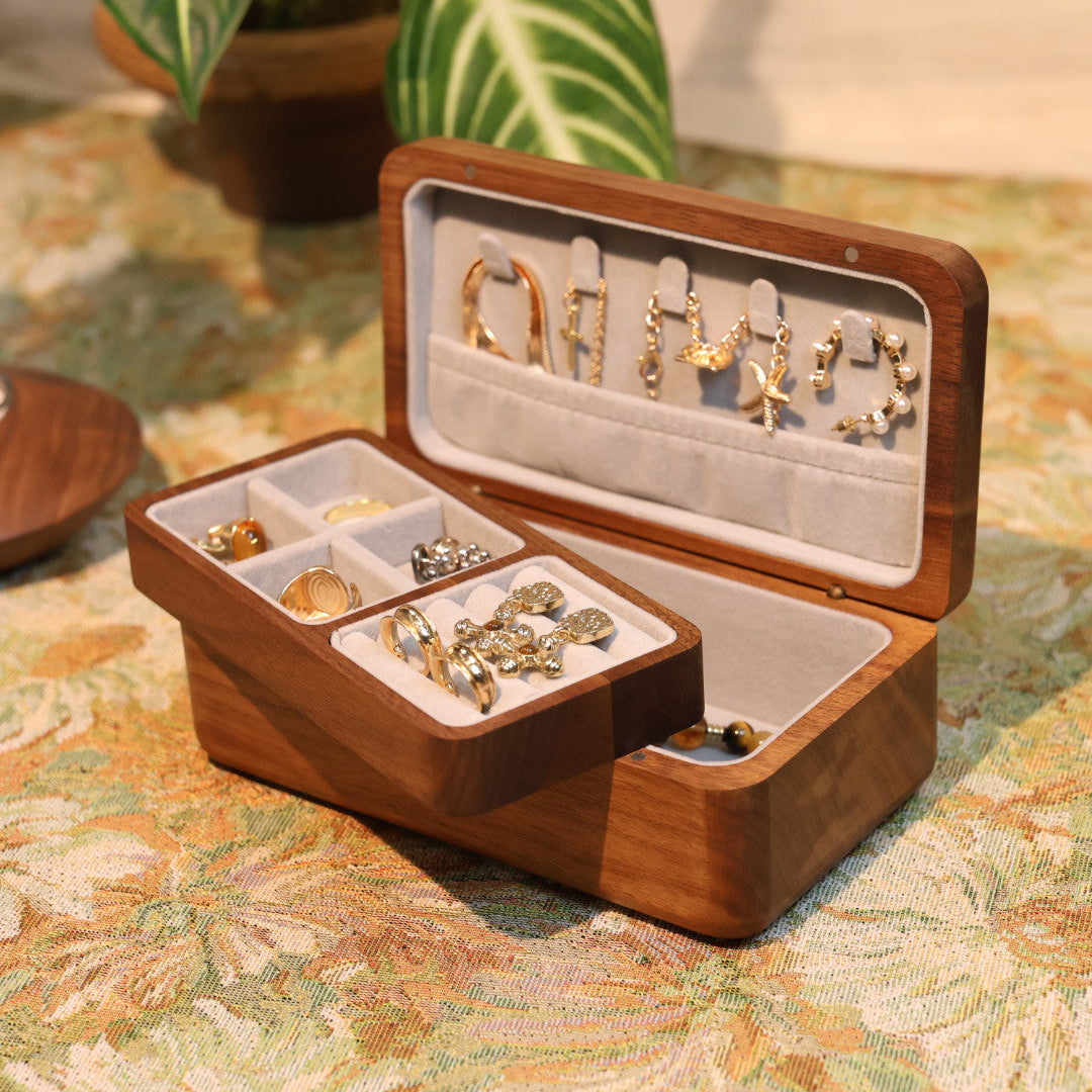 Wooden jewelry box with open lid displaying various earrings on a patterned surface.