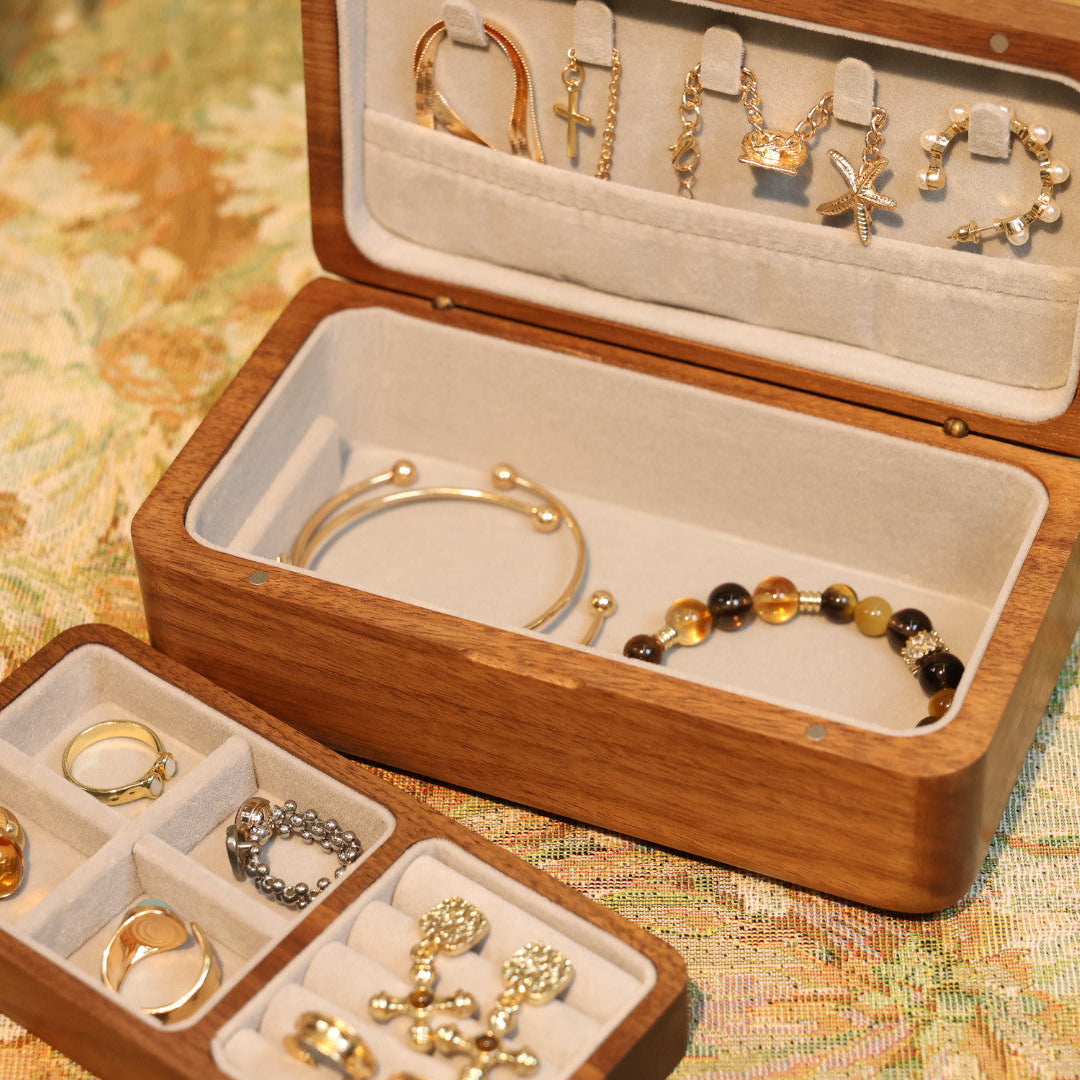 Wooden jewelry box with various jewelry items on a patterned surface