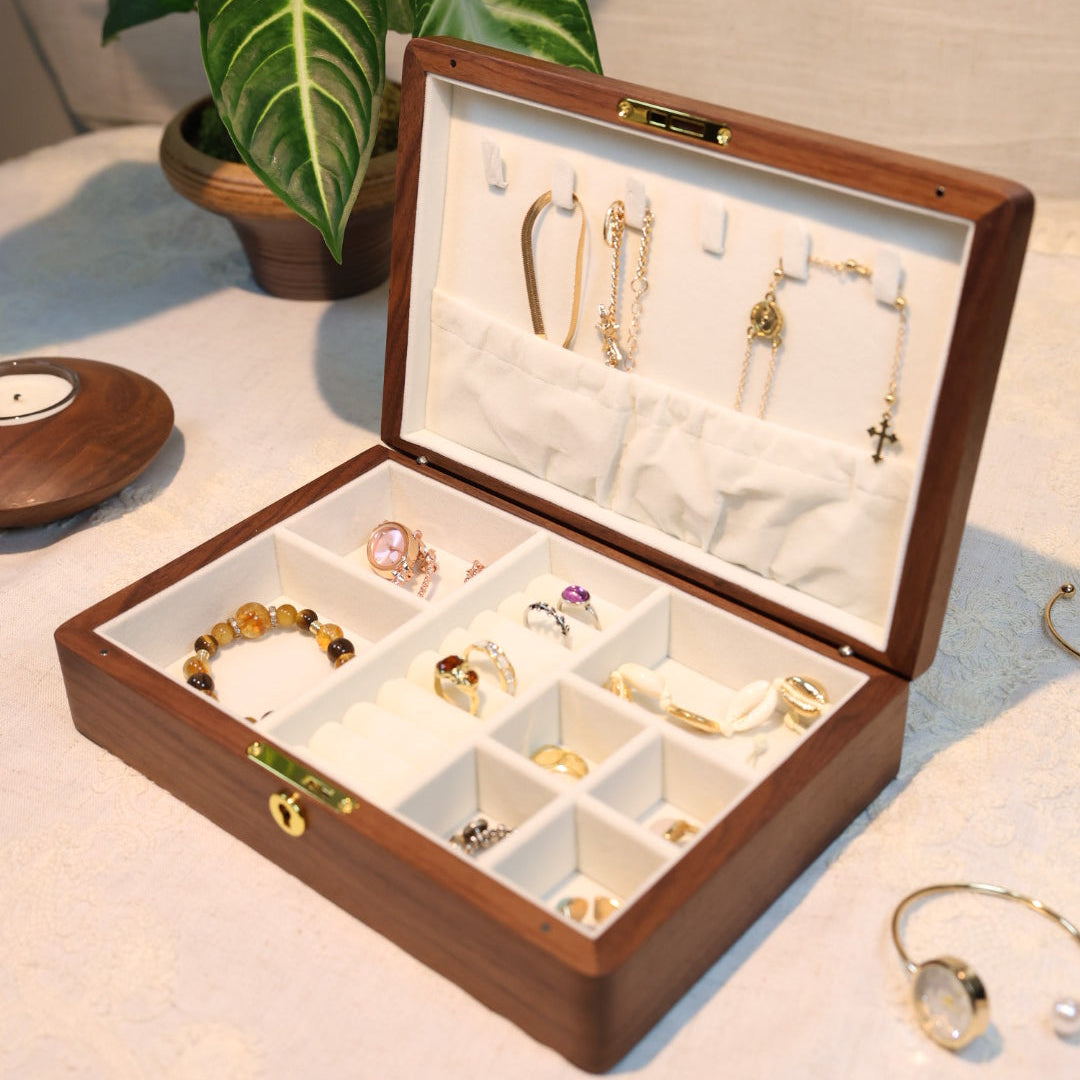 Open jewelry box with gold jewelry on a light surface with a plant in the background