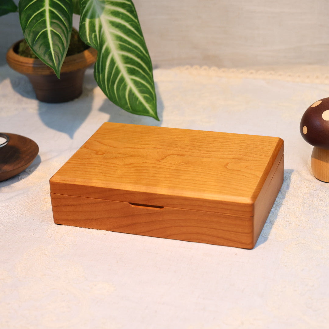 Wooden box on a light surface with decorative items like a candle and plant.