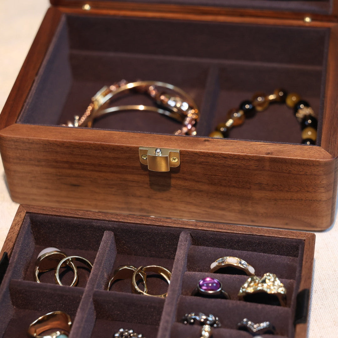 Wooden jewelry box with rings and bracelets on a light background