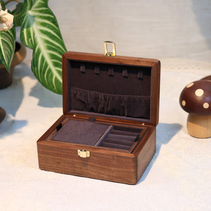 Wooden jewelry box on a light surface with decorative items around