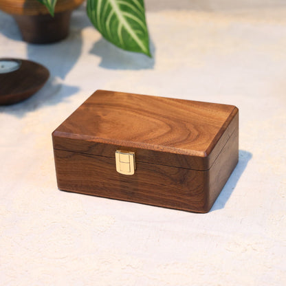 Wooden box with a gold clasp on a light surface with decorative items around