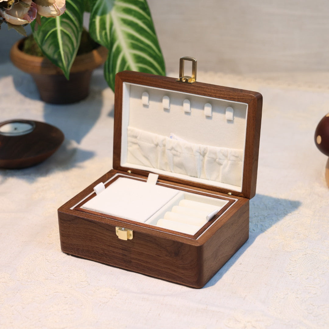Wooden jewelry box with a mirror on a white surface with decorative items around.