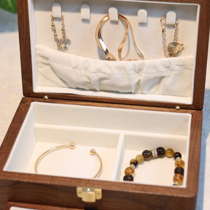 Wooden jewelry box with gold earrings and a bracelet on a light background