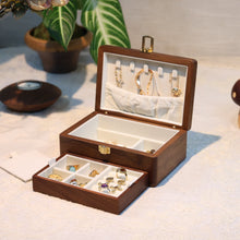 Wooden jewelry box with jewelry on a soft surface with plants in the background