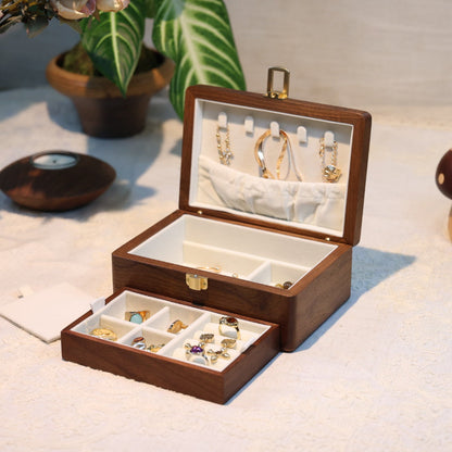 Wooden jewelry box with jewelry on a soft surface with plants in the background