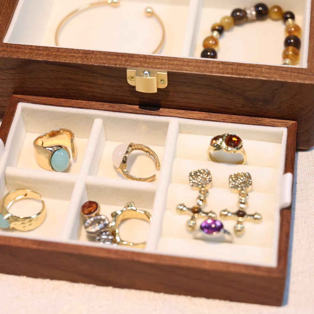 Wooden jewelry box with various rings displayed on a light background