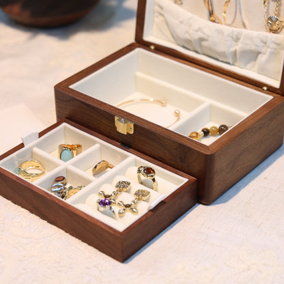 Wooden jewelry box with compartments containing earrings on a light surface