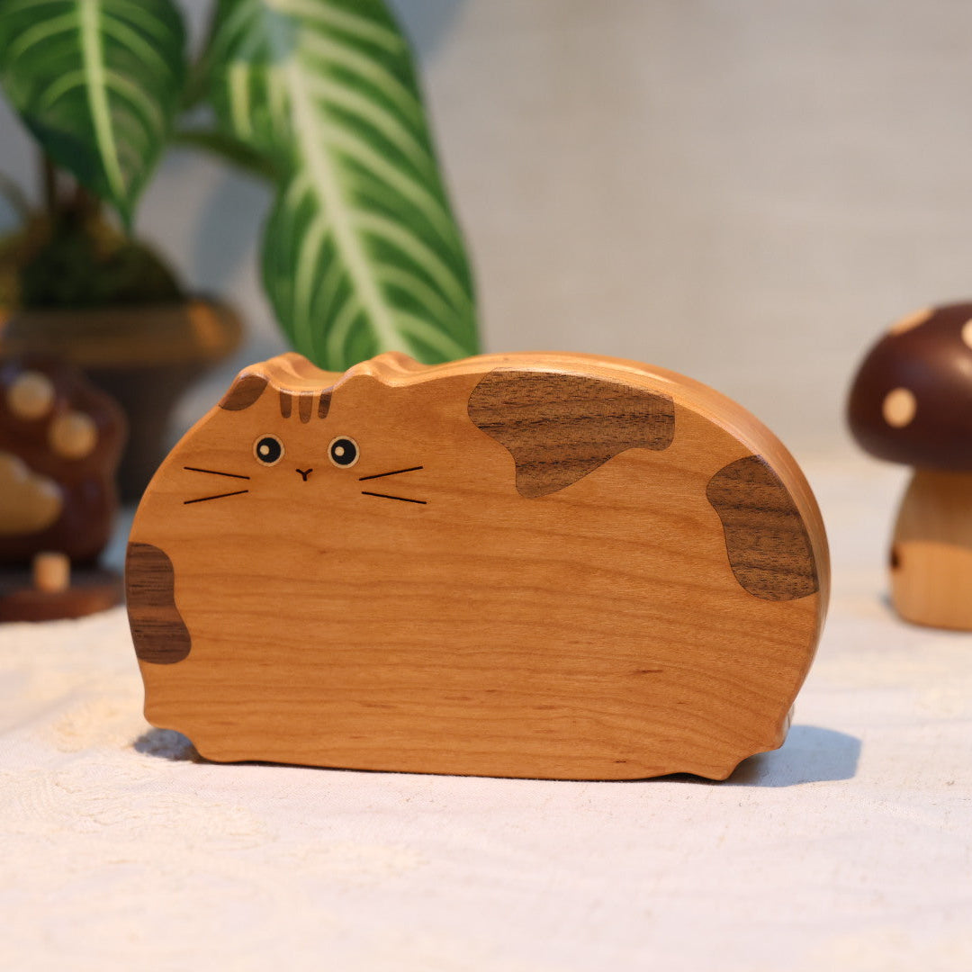 Wooden cat-shaped object with a mushroom and paw print decoration on a light background
