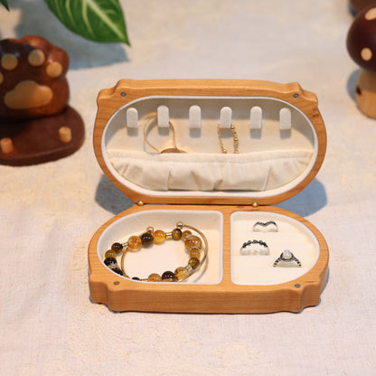 Open wooden jewelry box with a bracelet and earrings on a light background