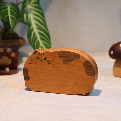 Wooden cat-shaped object on a light surface with decorative items in the background