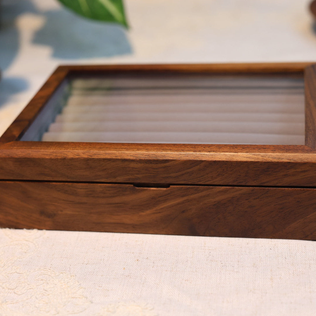 Wooden jewelry box with a glass lid on a light fabric background