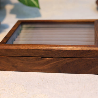 Wooden jewelry box with a glass lid on a light fabric background