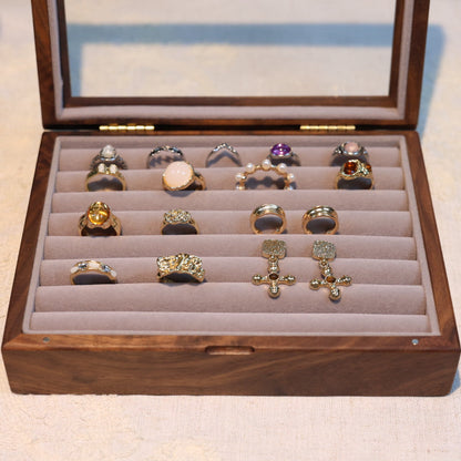 Wooden jewelry box with various rings displayed on a light background