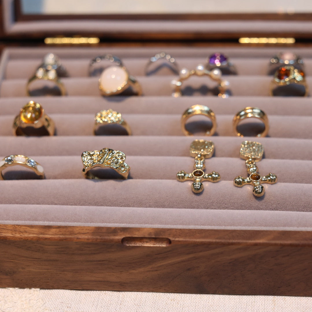 Wooden jewelry box with various rings displayed on a light background
