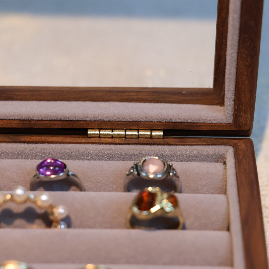 Open wooden jewelry box with rings inside on a light background