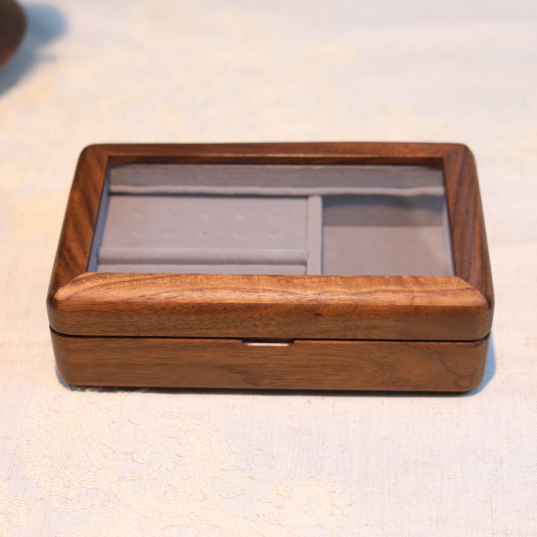 Wooden jewelry box with a glass lid on a light fabric background