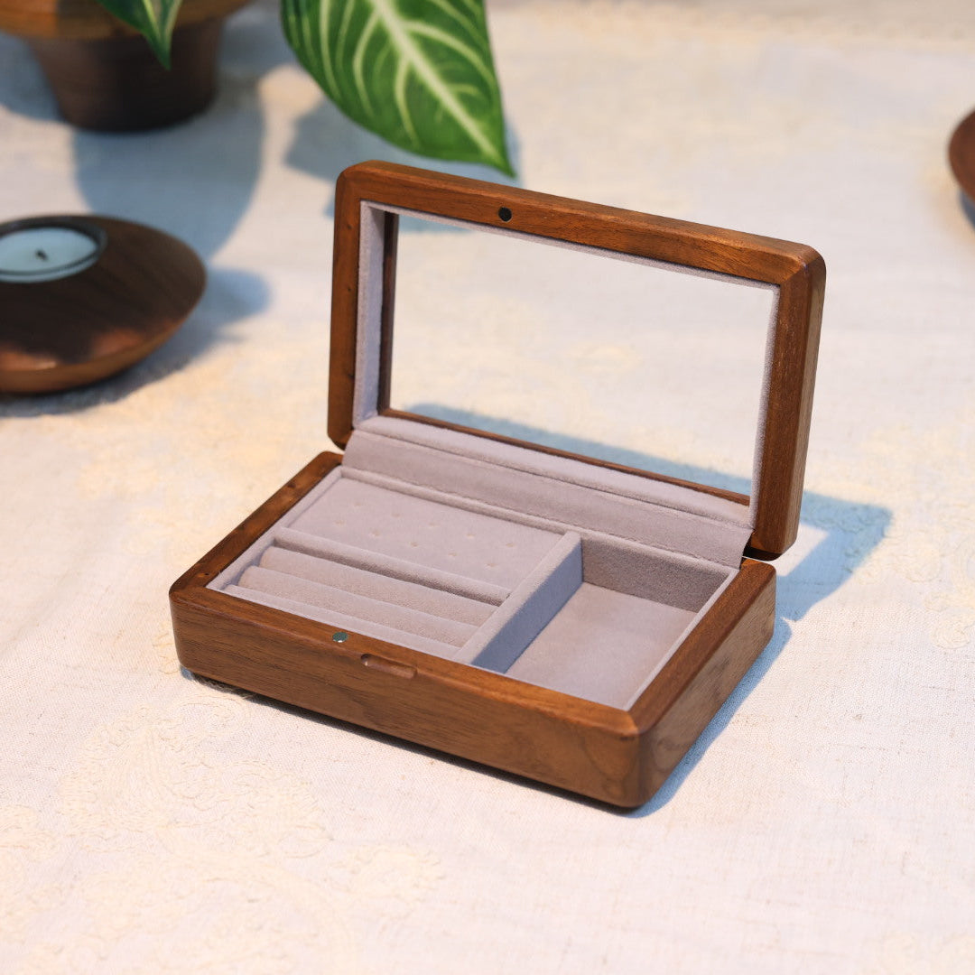 Wooden jewelry box with a clear lid on a light surface
