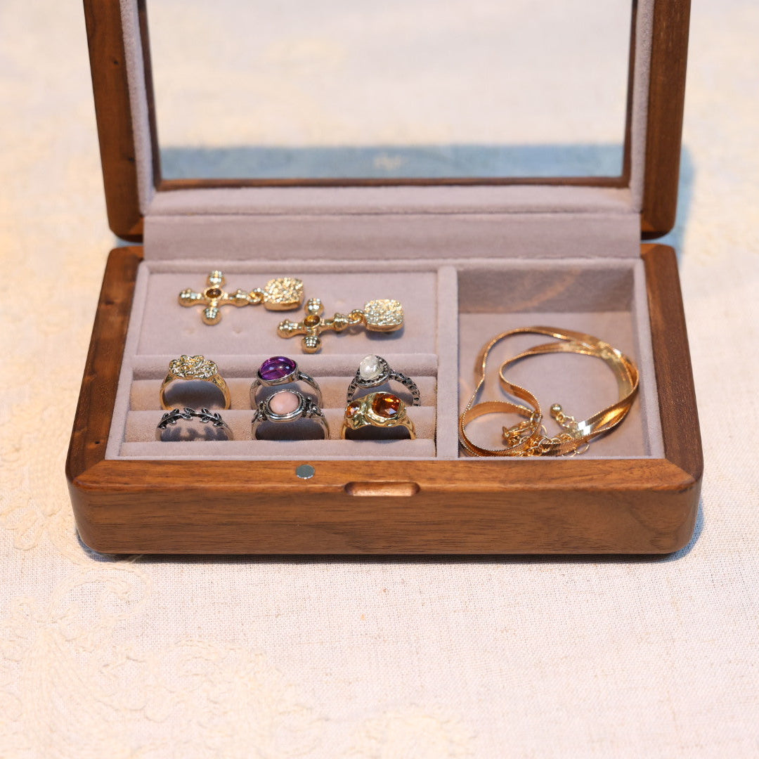Wooden jewelry box with various rings inside on a light background