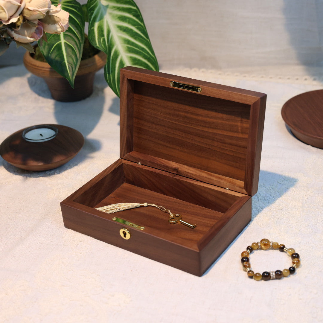 Wooden jewelry box on a table with a bracelet and earrings
