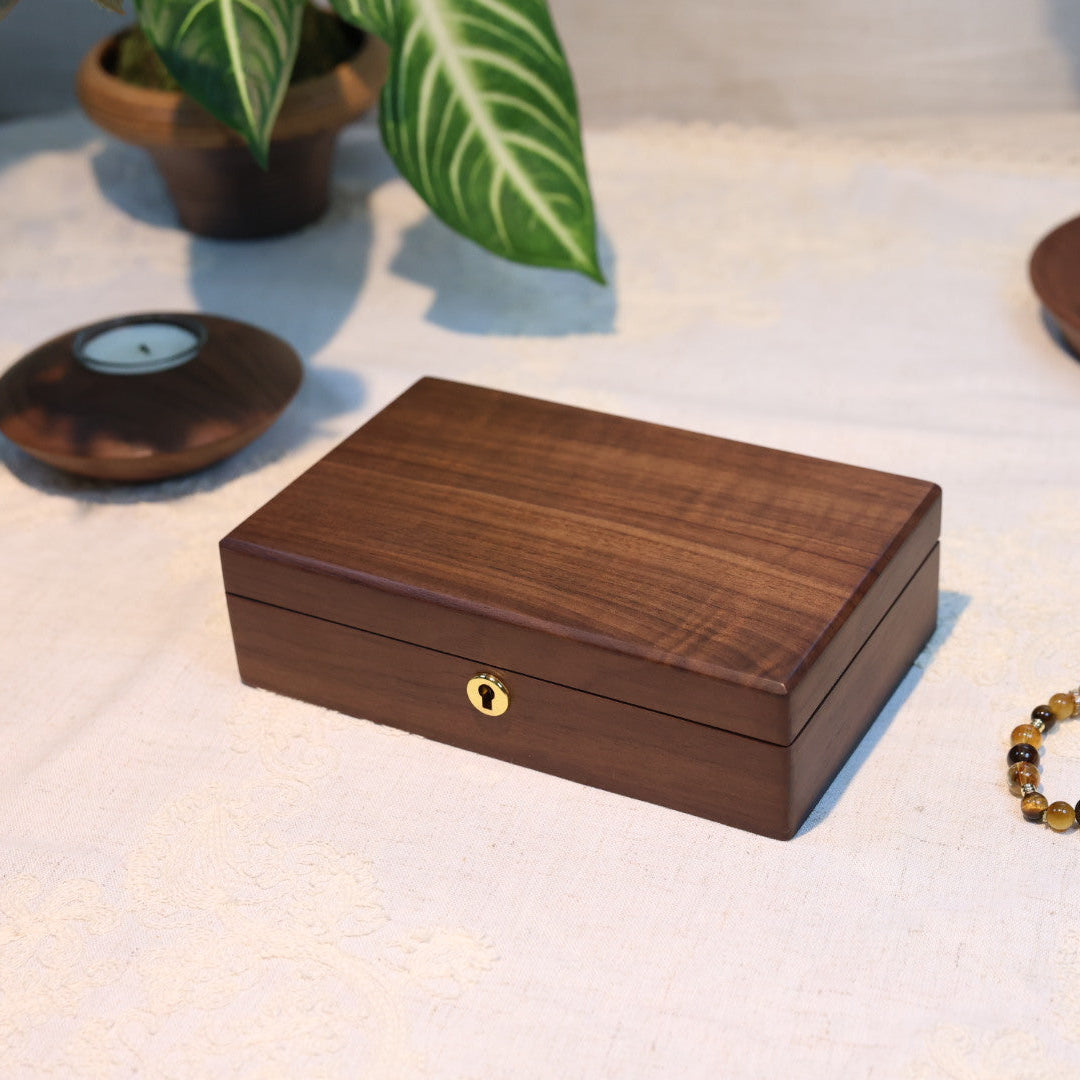 Wooden jewelry box on a light surface with a bracelet beside it