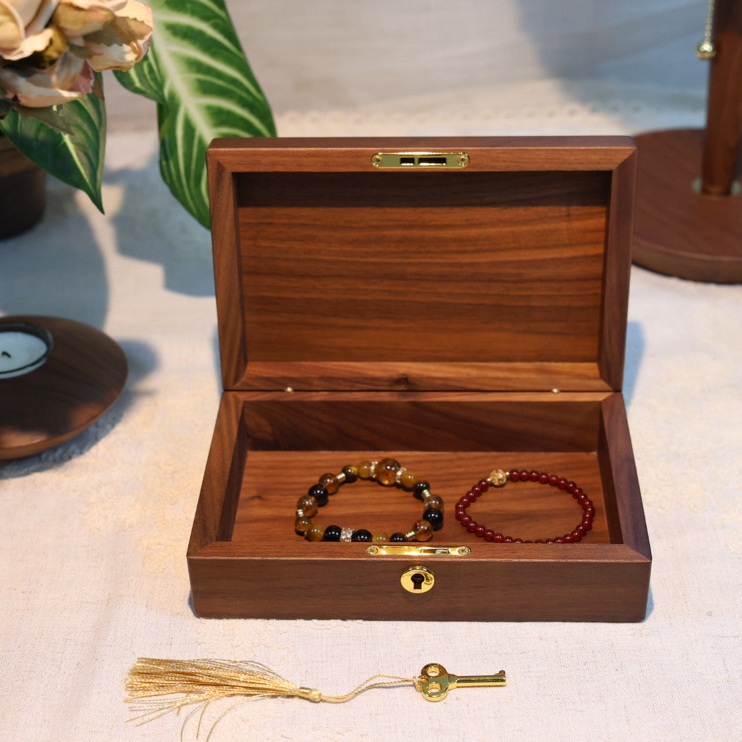 Wooden jewelry box with two bracelets on a textured surface.
