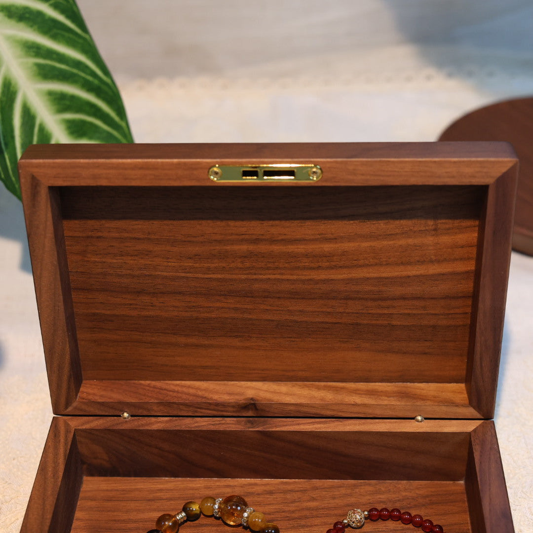 Wooden jewelry box with jewelry inside on a light surface