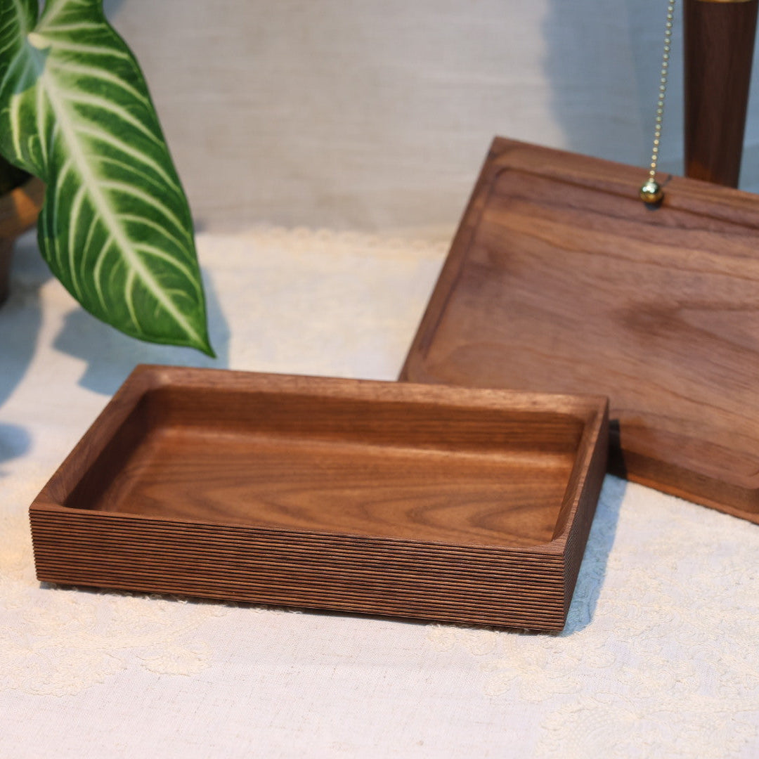 Wooden trays on a light surface with a plant in the background