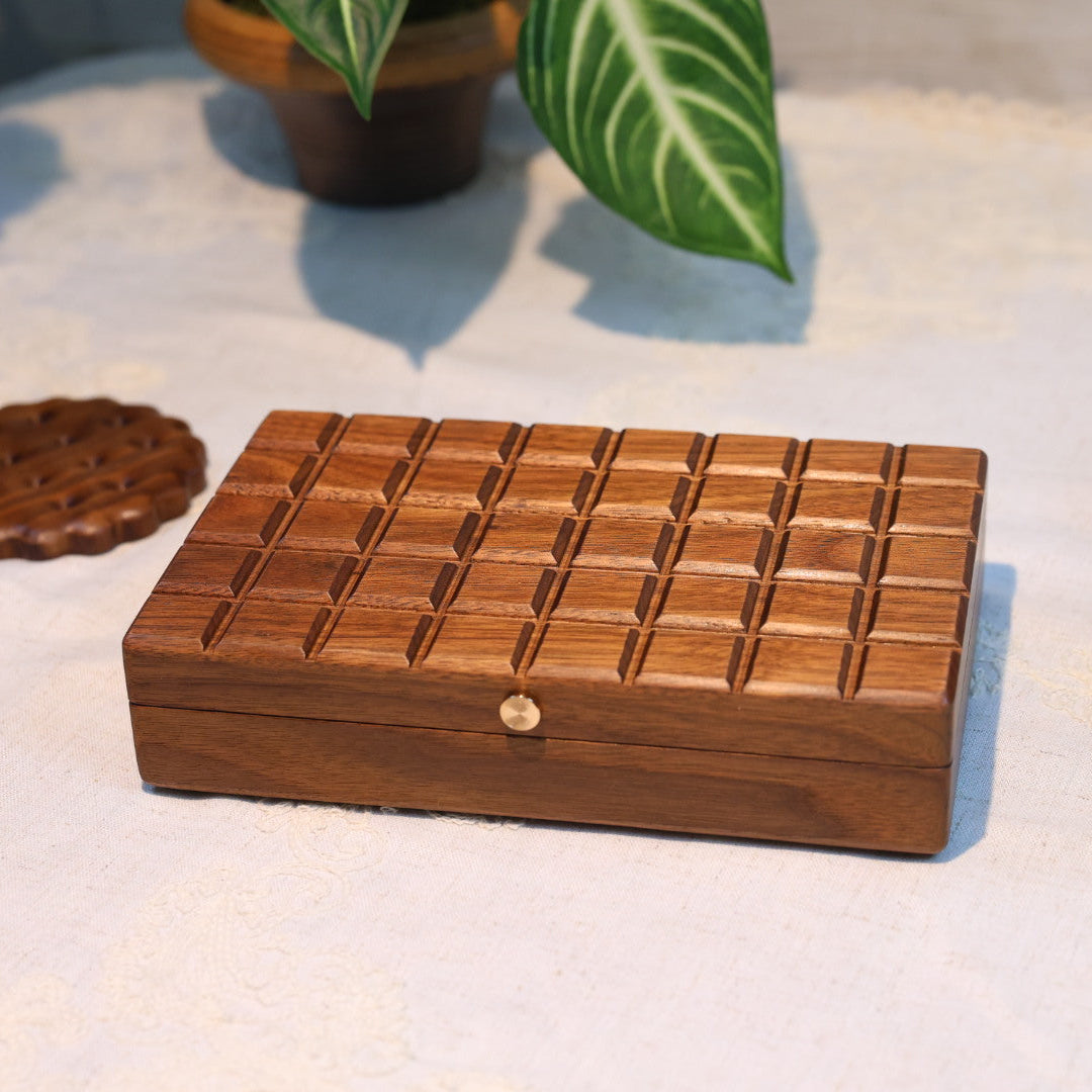Wooden jewelry box on a light surface with plants in the background