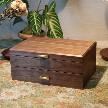 Wooden jewelry box on a decorative table with plants and a vase in the background