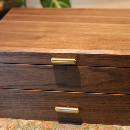 Wooden jewelry box with gold accents on a patterned surface