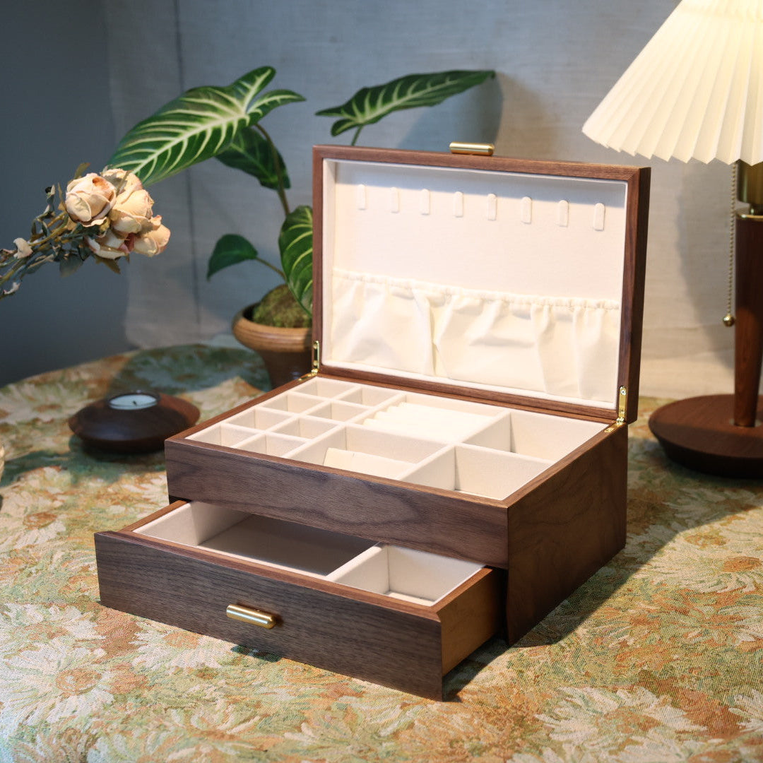Wooden jewelry box on a table with plants and a lamp in the background